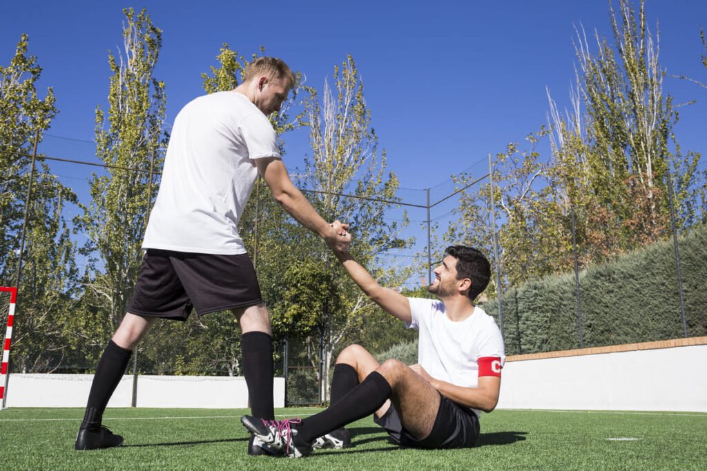 Jugador ayudando a levantarse a un compañero: recuperar la confianza tras un error